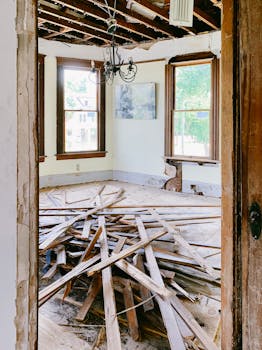 Interior room under renovation with exposed beams and planks piled on the floor.